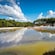 A geothermal area with a pool, a green forest and people on walking tracks